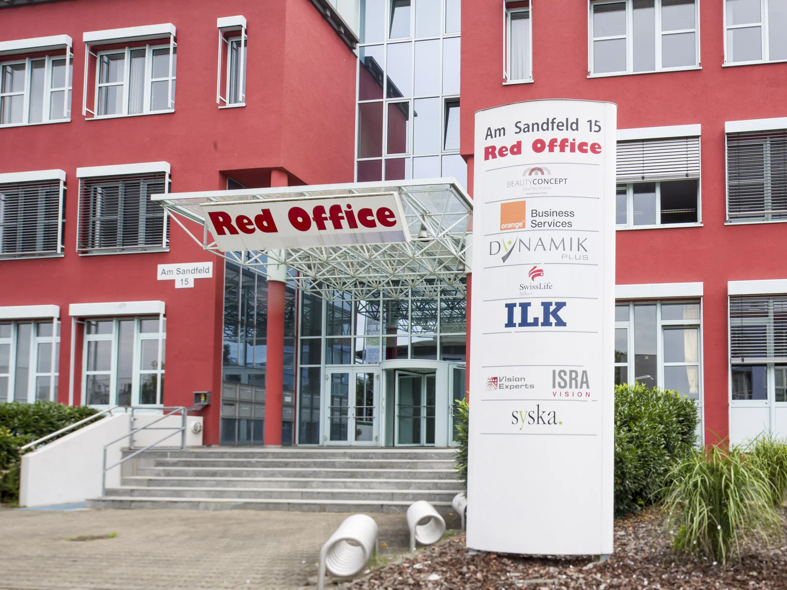 Eingang des Red Office mit Säulen-Entrée und Stelen-Beschilderung der Mieter